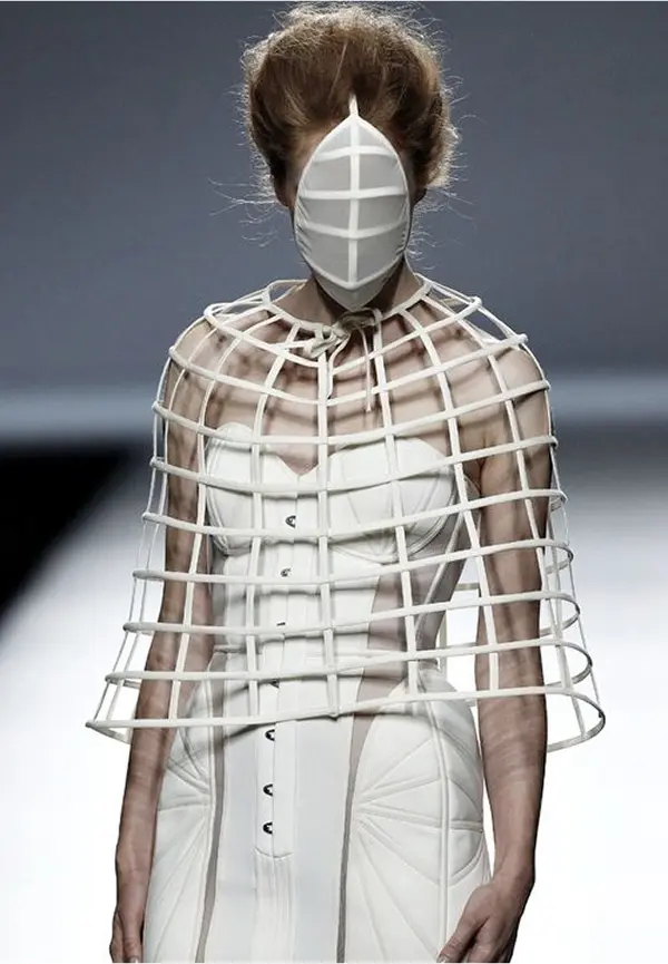 femme masquée d'un masque blanc, portant une robe blanche bustier et une cape en grillage blanc