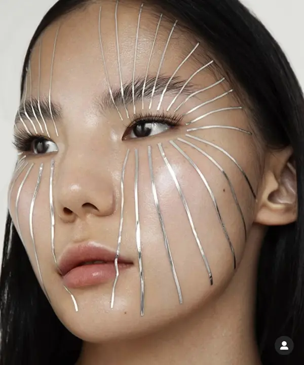 visage d'une femme avec un rayonnement métalique partant du centre de son visage (makeup)