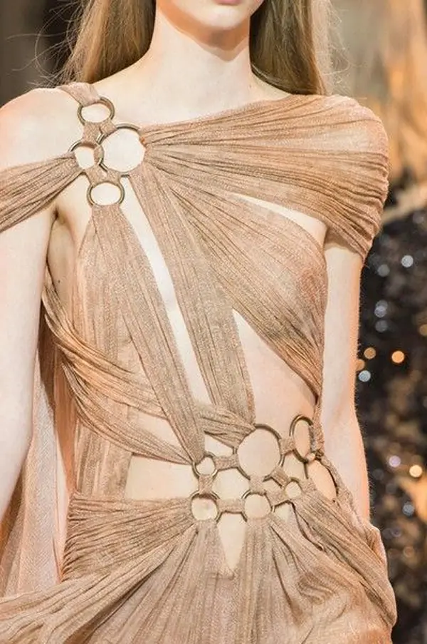 femme portant une robe beige composée d'anneaux dorés reliés entre eux par du tissus